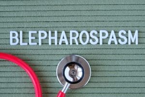 Blepharospasm- text from white letters on green background with stethoscope, medical concept diagnostics, treatment, healthcare. why does my eye keep twitching